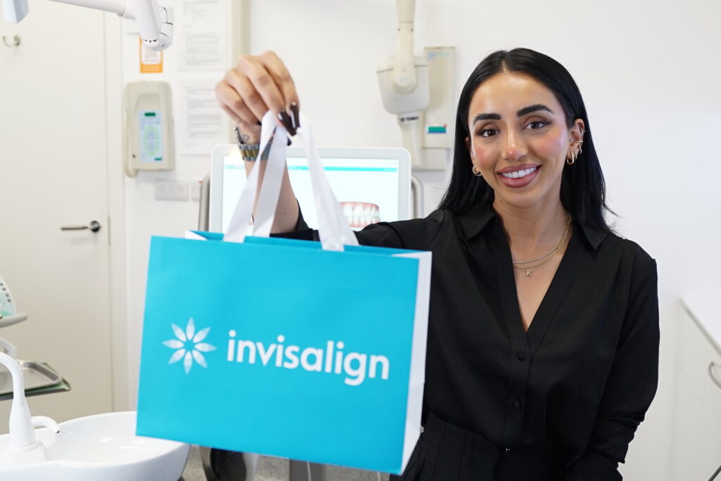 A MiSmile patient inside a member clinic holding an Invisalign case